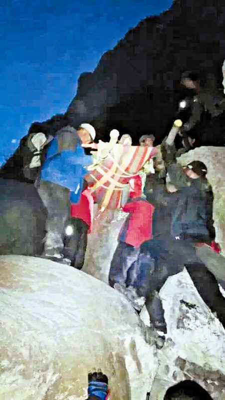 救援隊(duì)員用自制的簡(jiǎn)易擔(dān)架抬傷者。